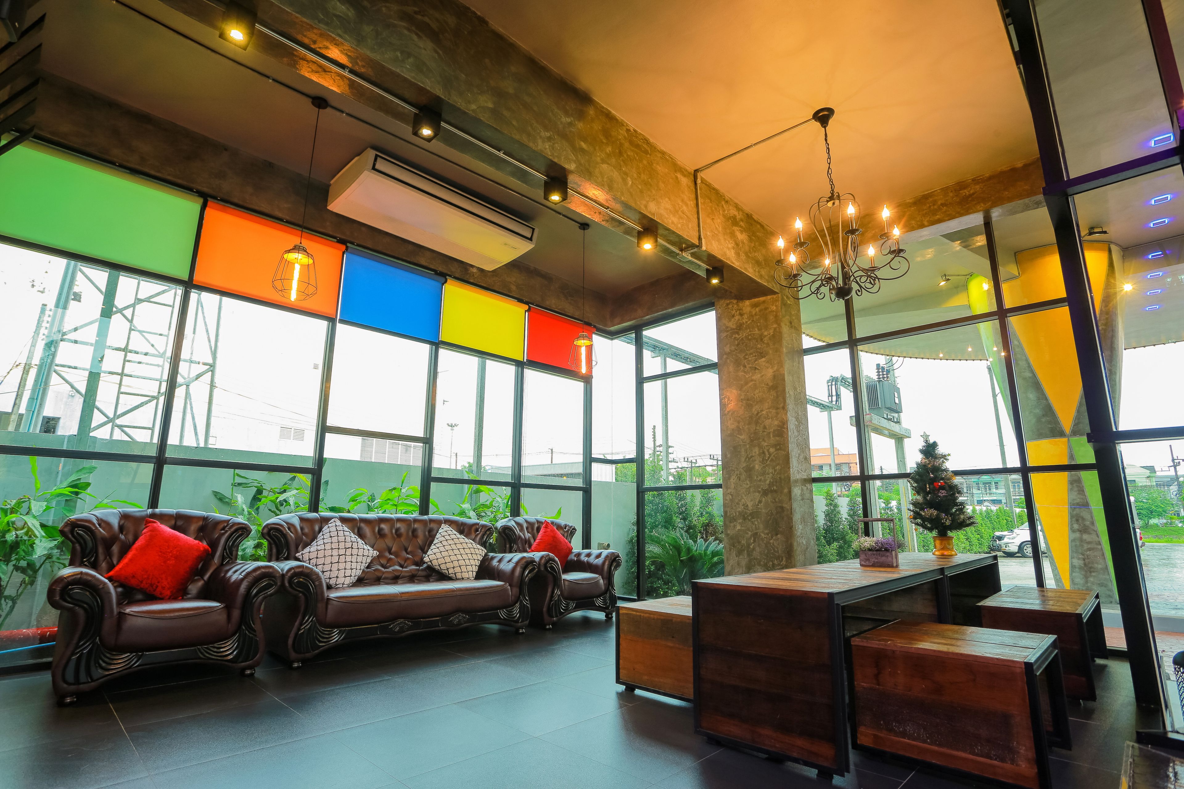 Un interior moderno con sofás de cuero, una mesa de madera y ventanas amplias que ofrecen vistas a zonas verdes y un edificio.