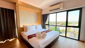 A hotel room with a large bed, a view of the city through large windows, and an air conditioning unit on the wall. - PS Extra Hotel (Hat Yai)
