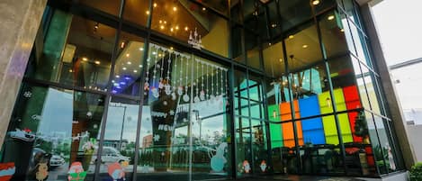 Un edificio moderno con amplios ventanales, una escalera que conduce a la entrada y decoraciones festivas.