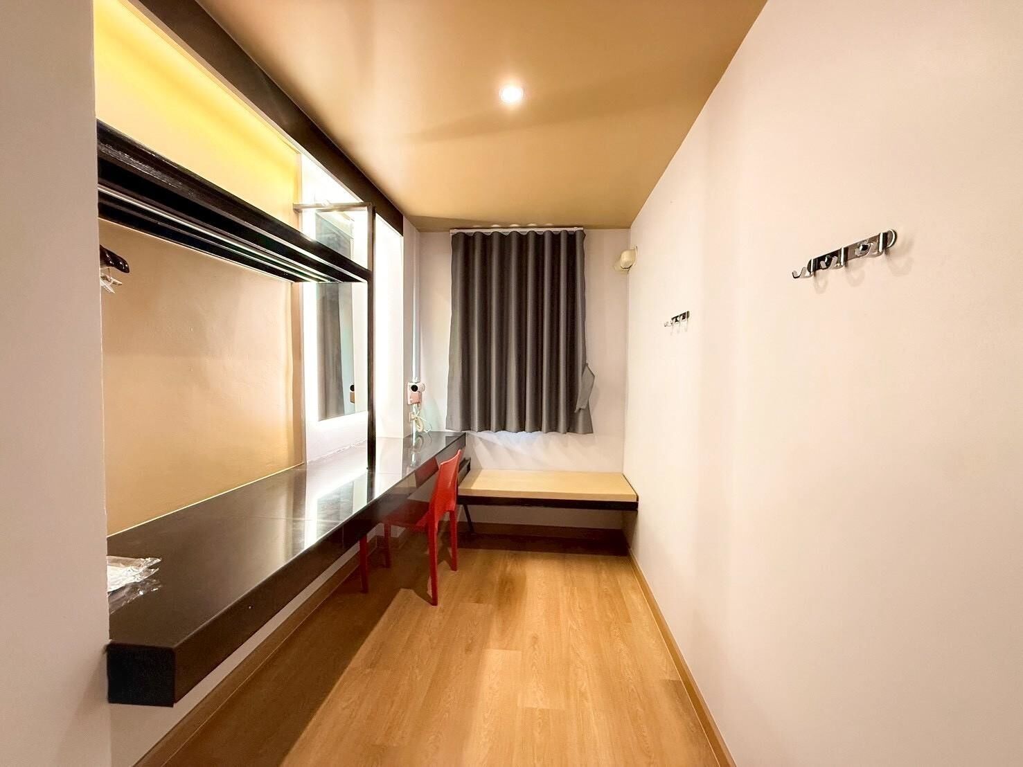 Una habitación de hotel pequeña con cama, un escritorio, un espejo y una ventana con cortinas.