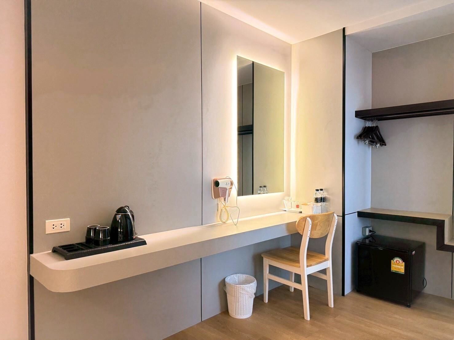A modern bathroom with a large mirror, a sink, a chair, and a small cabinet.
