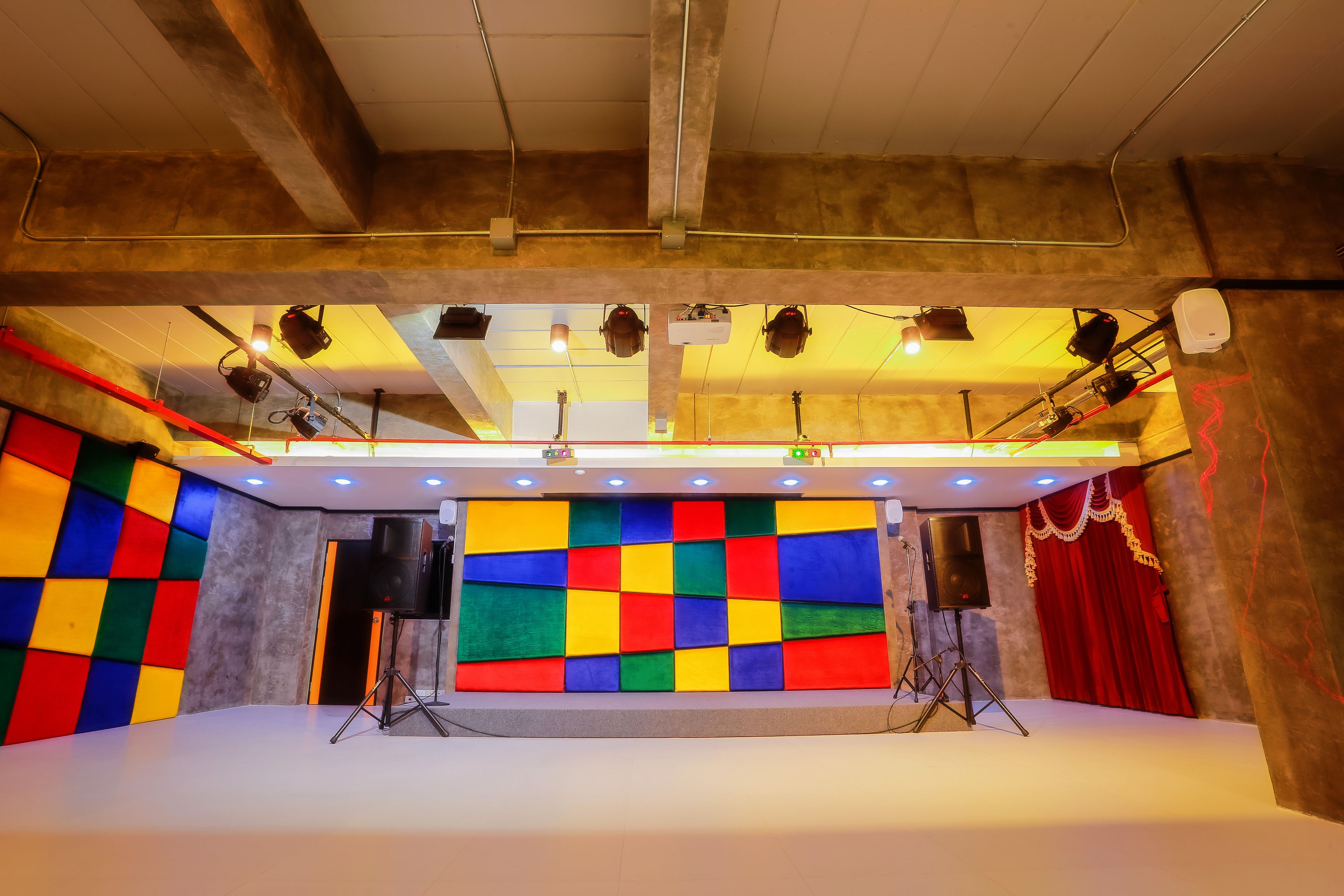 Un escenario con paneles de colores, equipo de iluminación y una cortina roja.