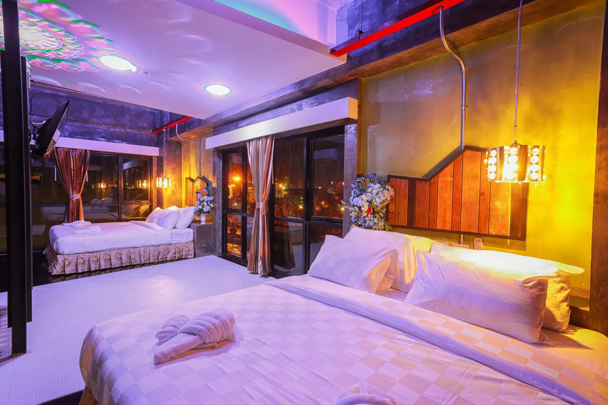 A hotel room with two beds, a large window, and a modern chandelier.