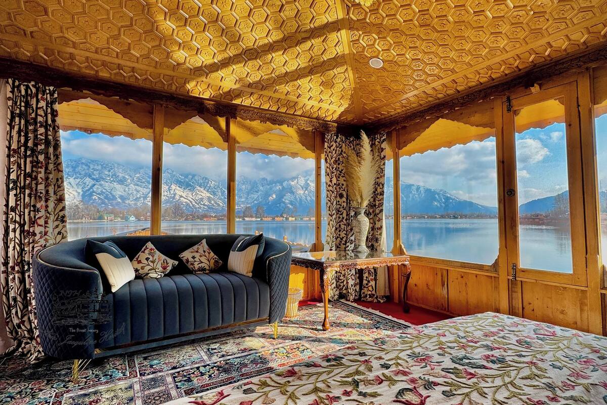 Um quarto com uma grande janela, um sofá, um candelabro e um tapete estampado.
