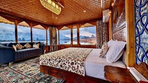 Un dormitorio con una cama grande, un sofá y vistas a montañas y un lago.
