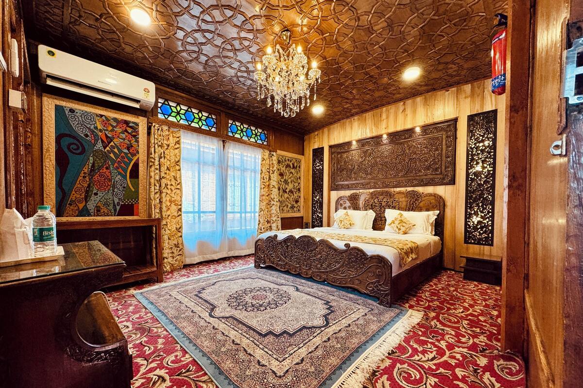 Quarto com uma cama grande, cabeceira ornamentada, tapetes estampados e um candelabro.