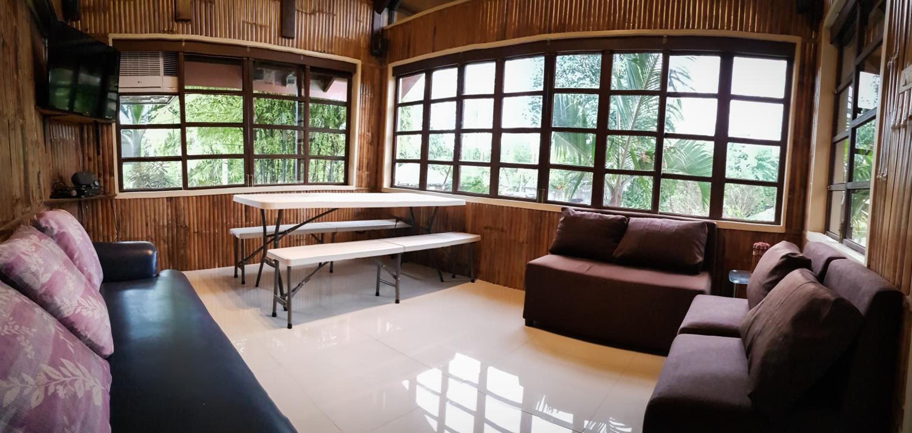 A room with a curved wooden wall, a bench, a sofa, and a table.
