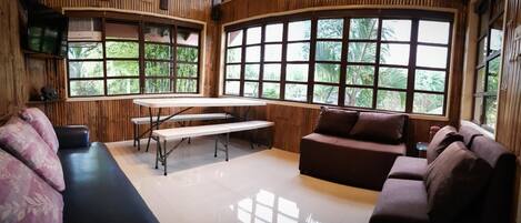 A room with a curved wooden wall, a bench, a sofa, and a table.