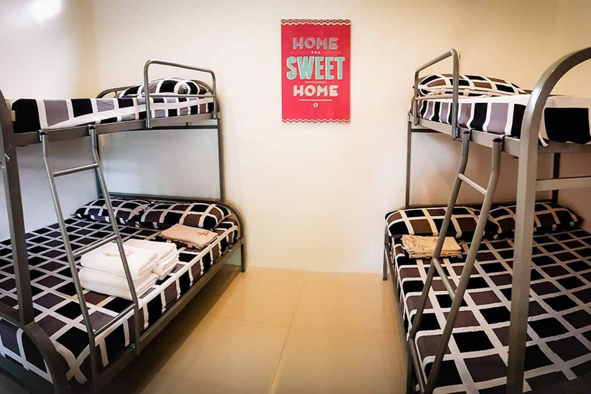 Quarto com beliche e placa na parede com a frase 'Lar Doce Lar'.