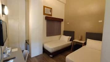Une chambre d’hôtel équipée d’un bureau, de deux lits simples, d’une petite table de chevet et d’un téléviseur fixé au mur.