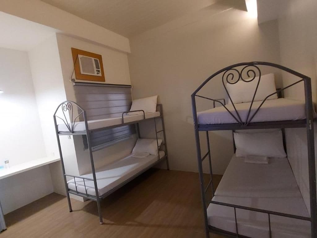 Una habitación con dos literas, una ventana y un aire acondicionado de pared.