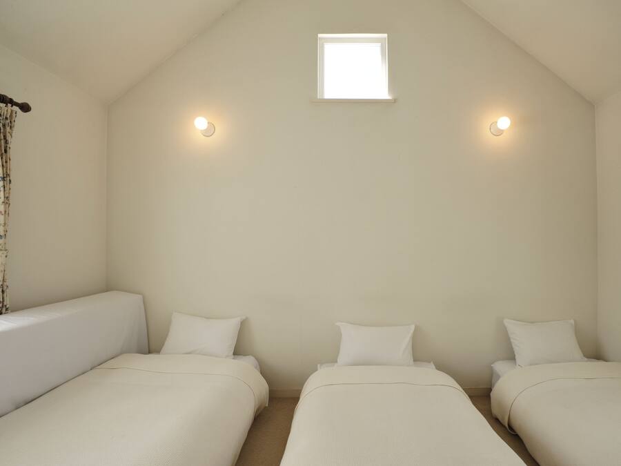 A room with two single beds, a small window, and two wall-mounted lights.