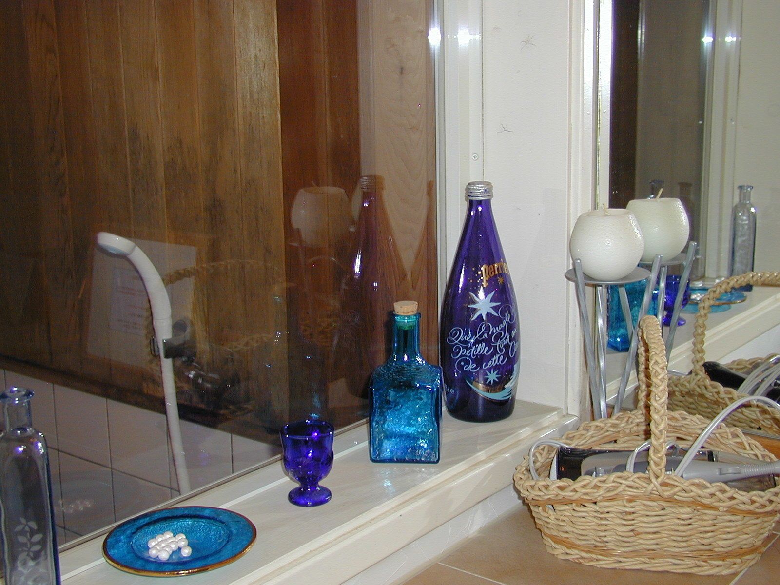 Een badkamer met een houten wastafelmeubel, een spiegel en diverse toiletartikelen op het aanrecht.