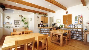 Une pièce chaleureuse et bien éclairée, avec des meubles en bois, une bibliothèque remplie de livres et un petit coin cuisine.