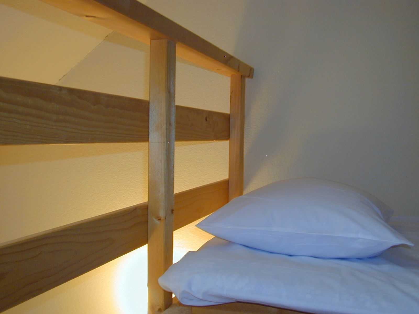 A bunk bed with wooden slats and white bedding.