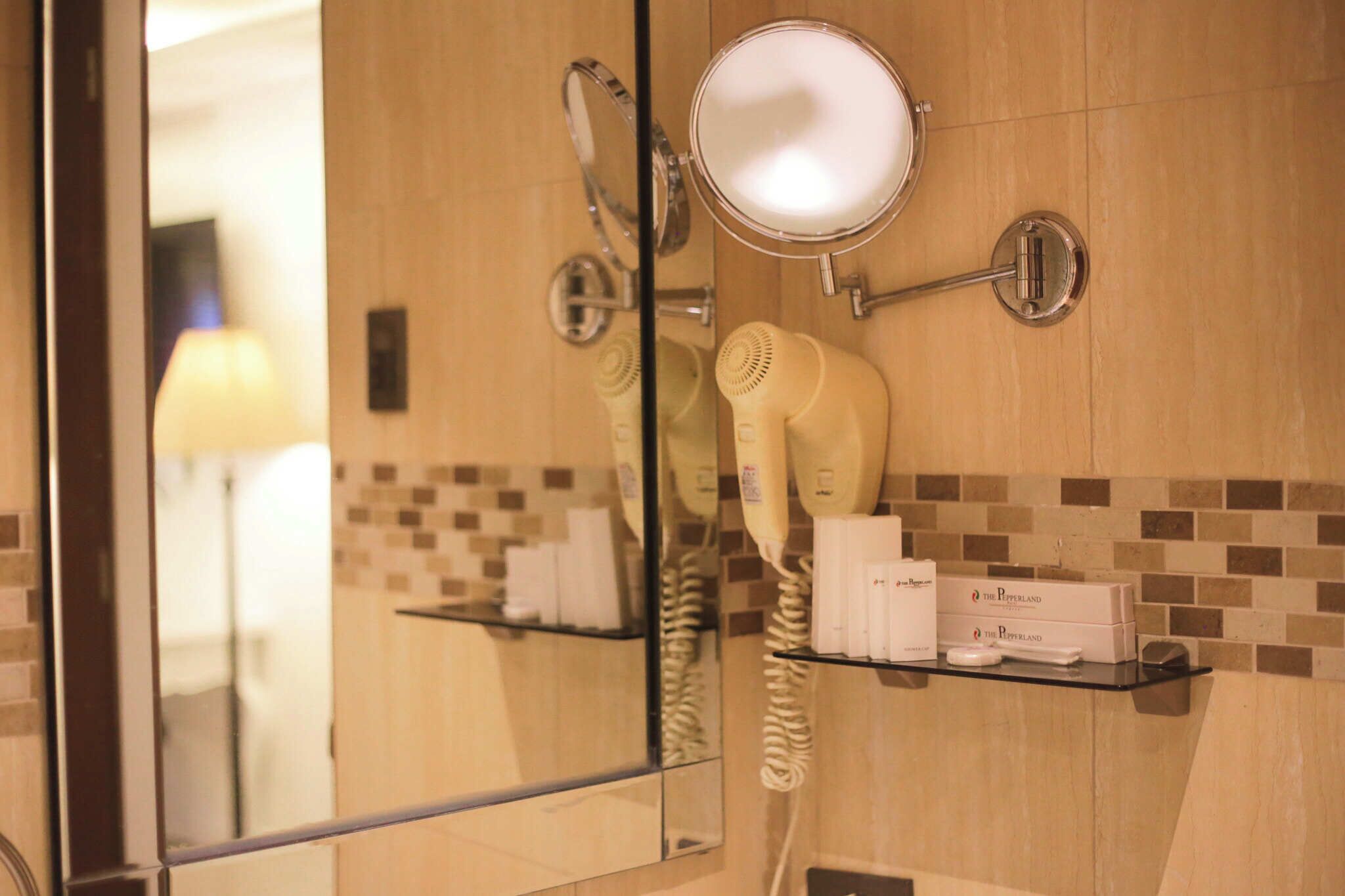 Casa de banho com secador de cabelo, espelho e um armário com produtos de higiene pessoal.