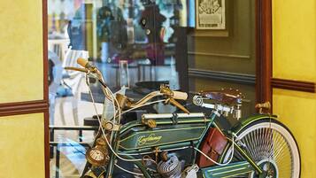 Une moto ancienne exposée dans une vitrine, avec un tableau encadré et une lampe en arrière-plan.