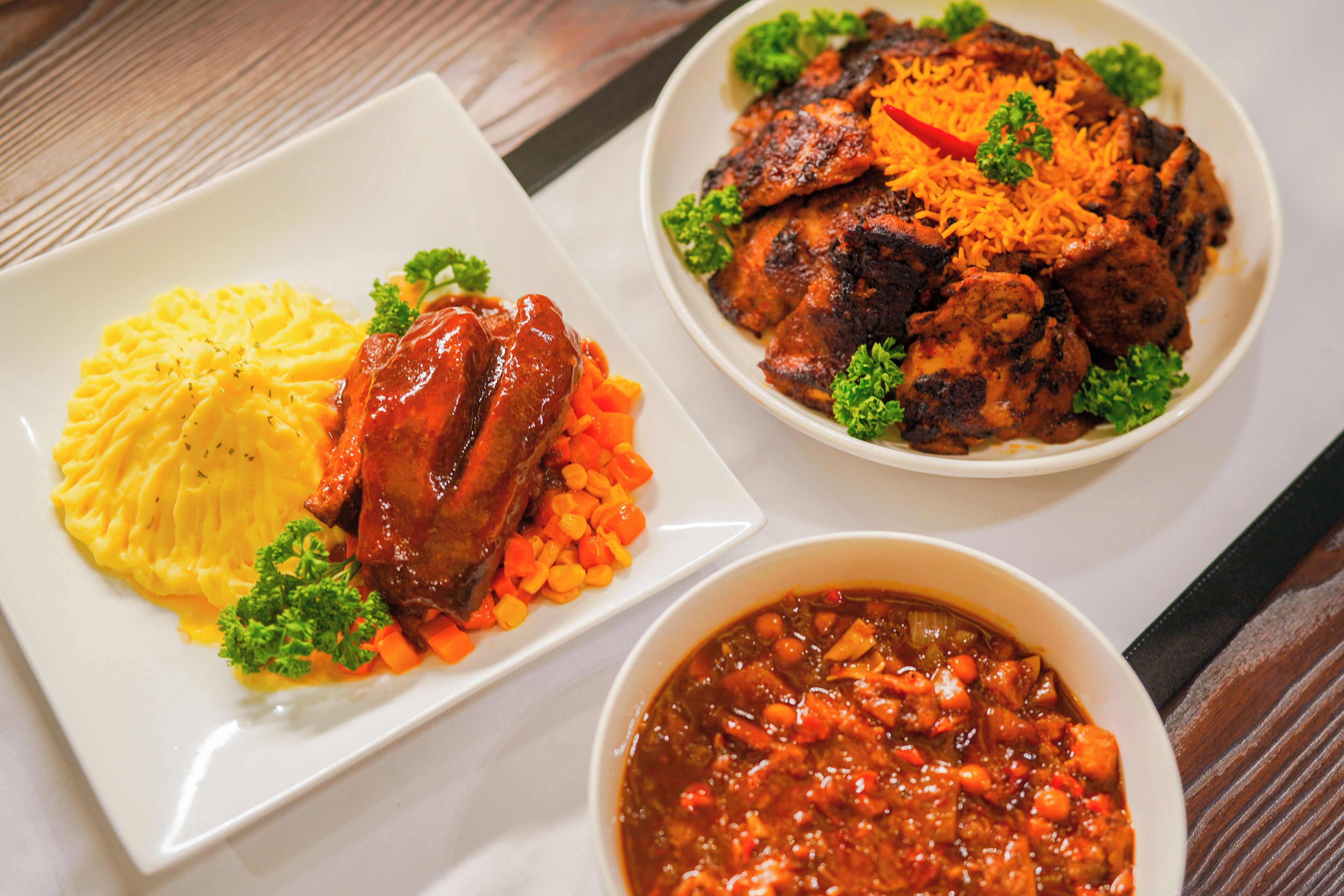 A plate of mashed potatoes with a meat dish and a bowl of stew.