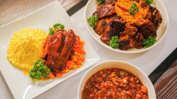 A plate of mashed potatoes with a meat dish and a bowl of stew.