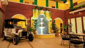 A vintage car, a fountain, and outdoor seating in a courtyard.