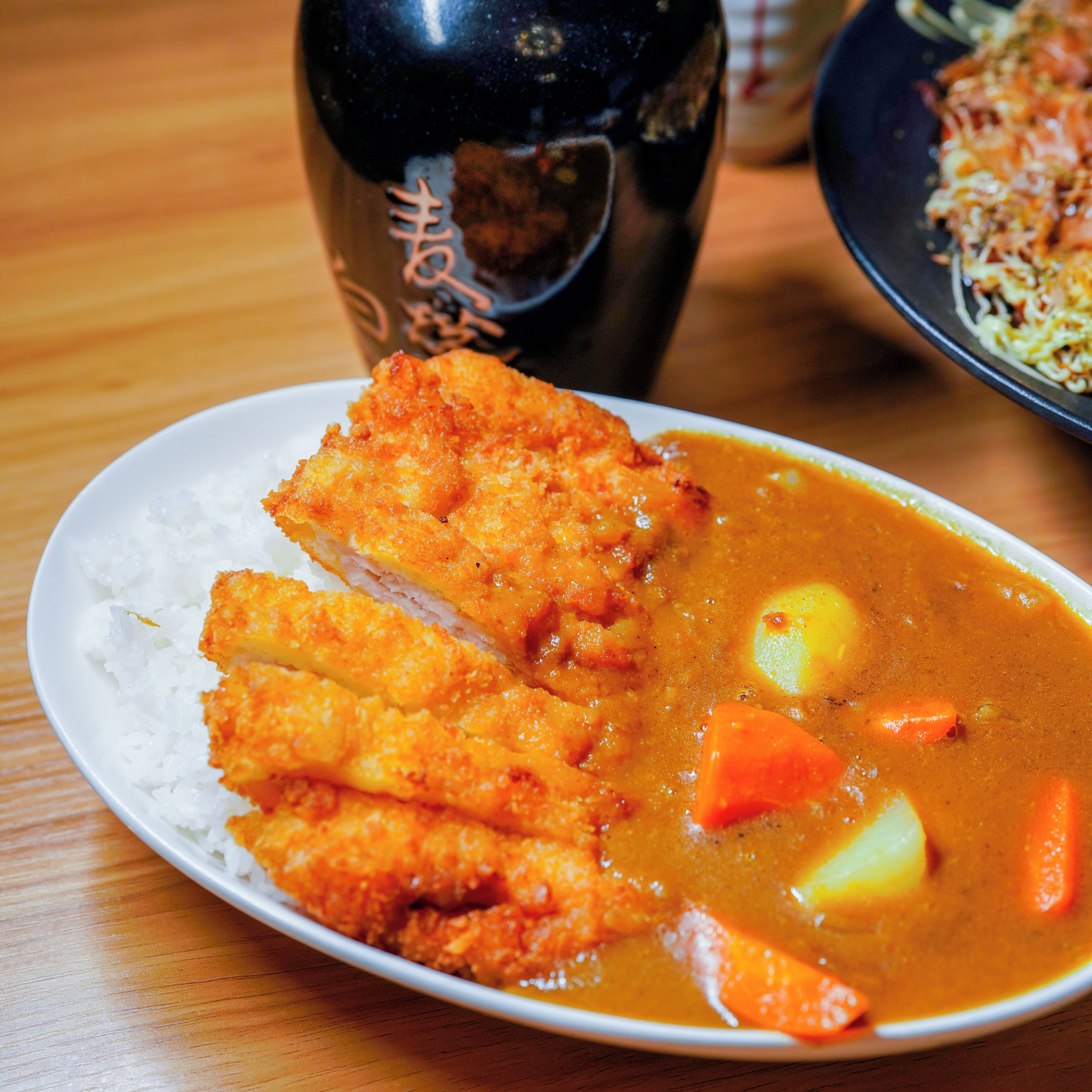 A plate of fried chicken with rice and a curry sauce.