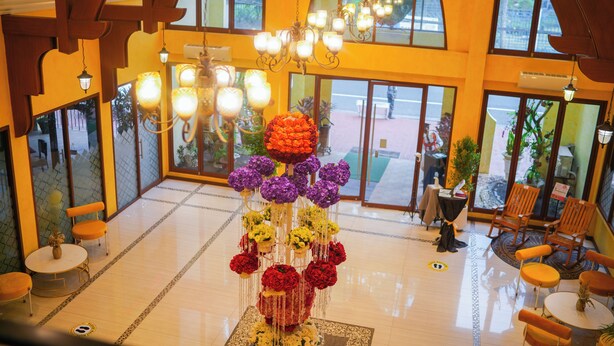 A lobby with a central floral arrangement, seating area, and large windows.