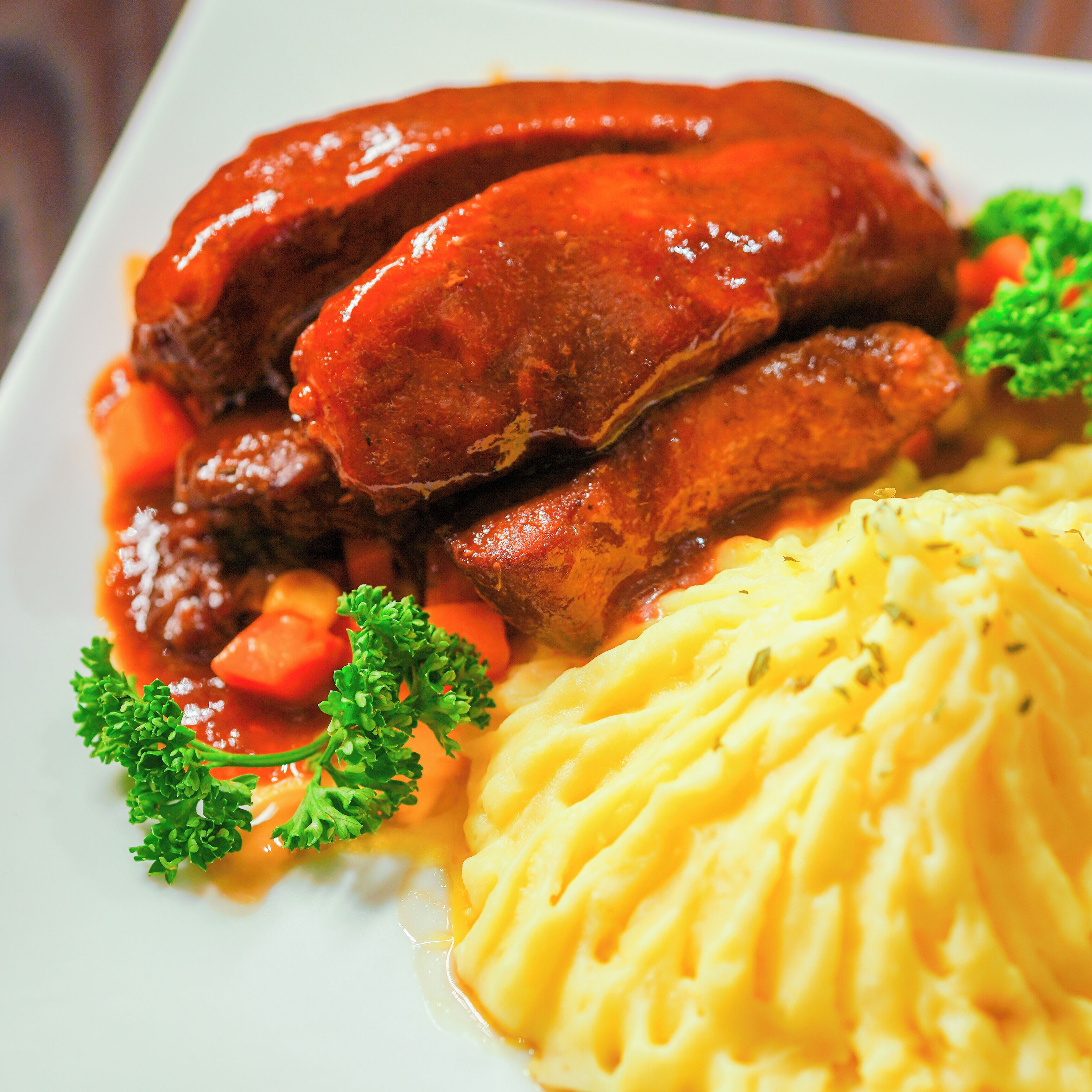 A plate of food with sausages, carrots, and mashed potatoes.