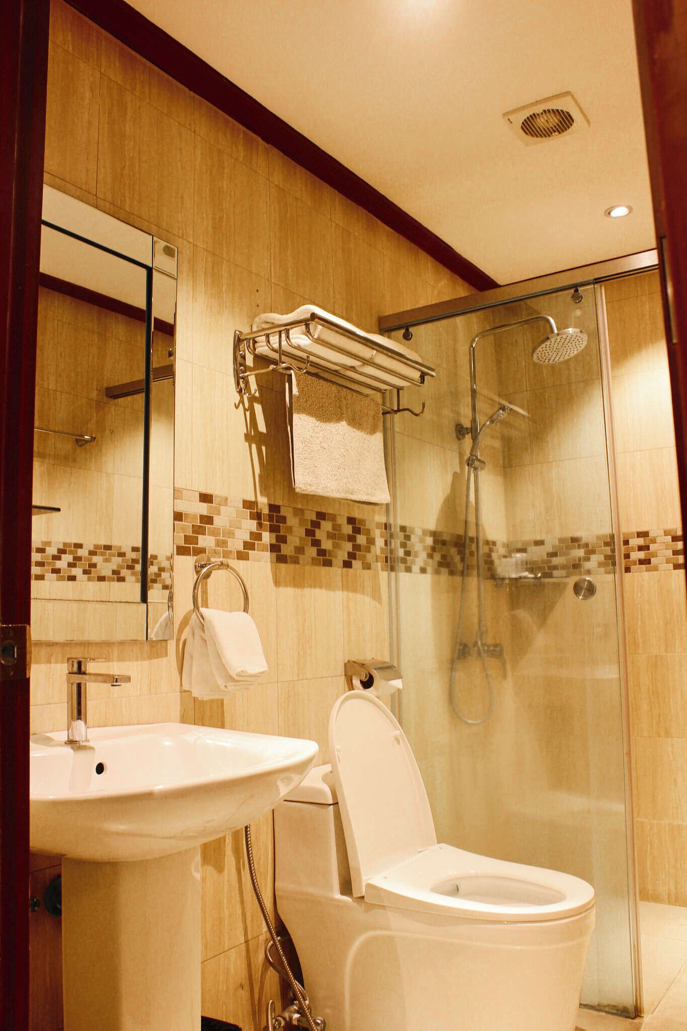 A modern bathroom with a glass-enclosed shower, a white sink, and a toilet.
