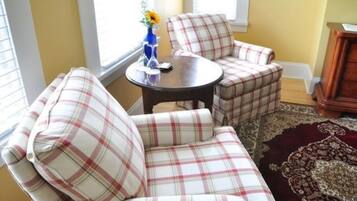 Un conjunto de sofá y sillón con estampado de cuadros en una habitación con una mesa de madera, un jarrón con flores y una alfombra estampada.