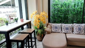 A modern living room with a sofa, patterned cushions, a coffee table, and a potted plant. - Mont Place Donmuang (Bangkok)