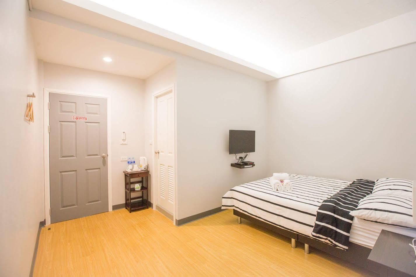 A hotel room with a bed, a TV, a small table with toiletries, and a door.