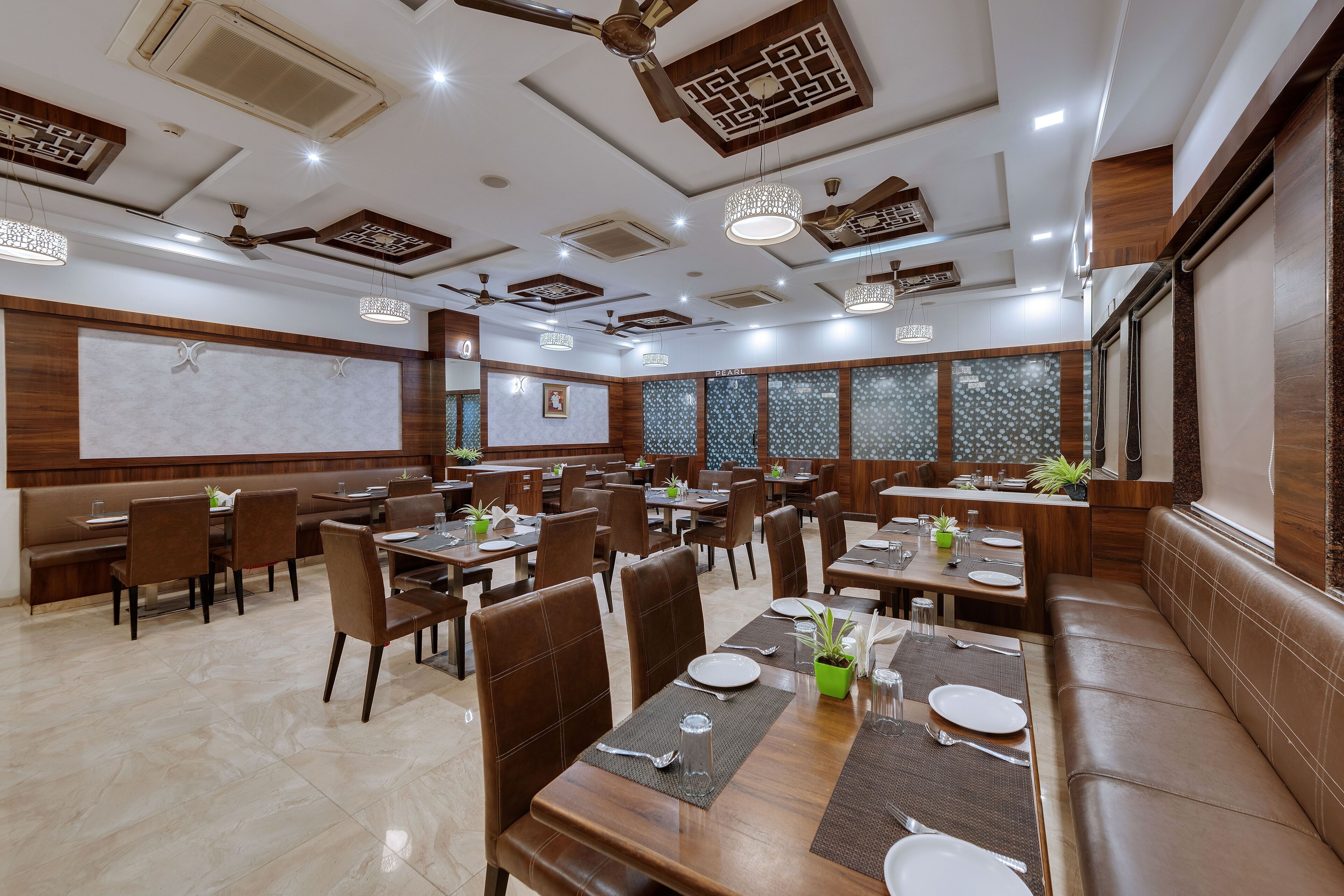 A restaurant with multiple dining tables and booths, ceiling fans, and decorative lighting fixtures.
