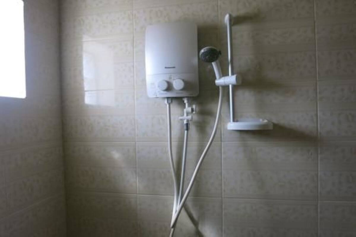 A bathroom with a wall-mounted heater, a handheld showerhead, and a white sink.
