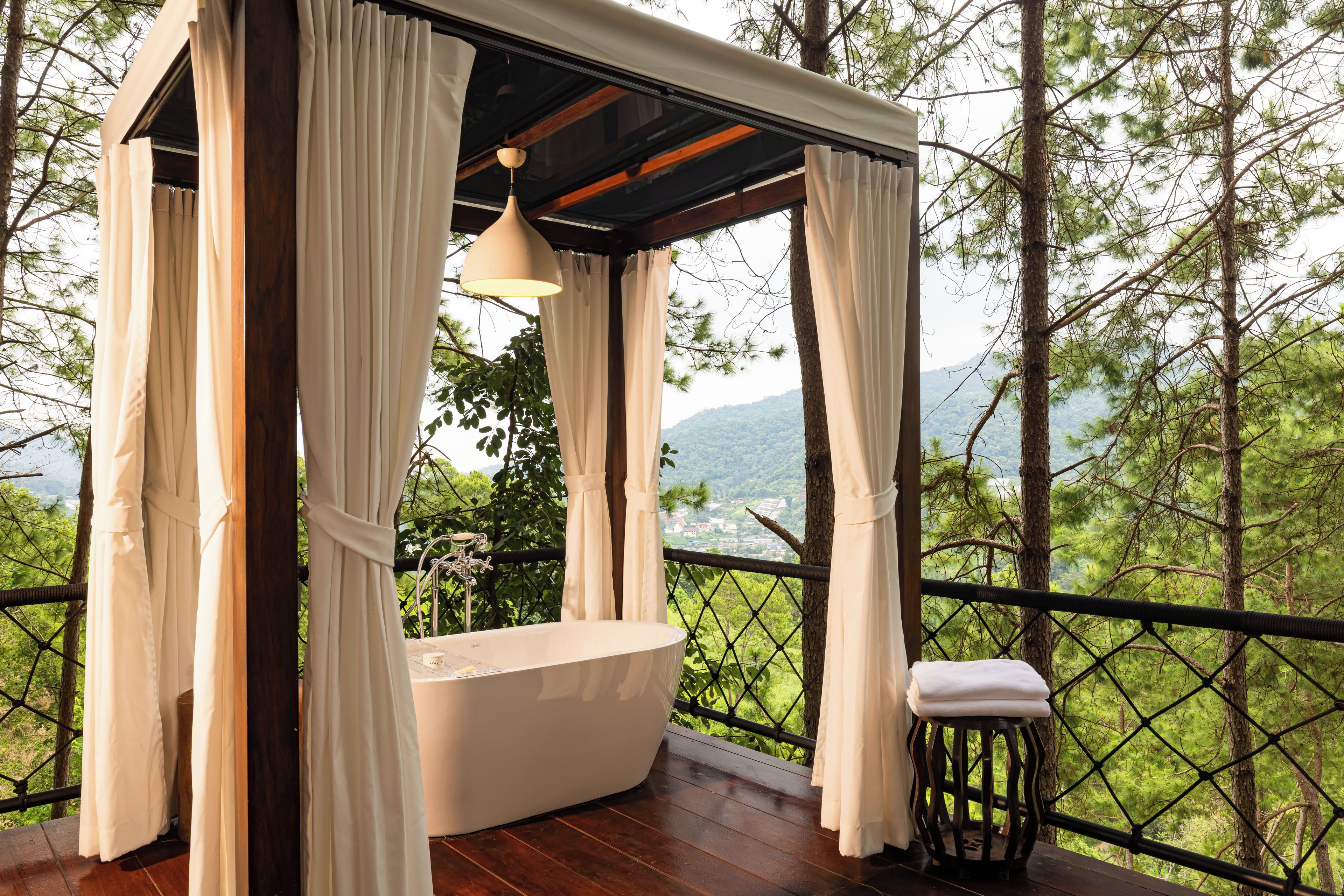 Un espace spa comprenant une baignoire, un plancher en bois et une vue sur un paysage boisé.
