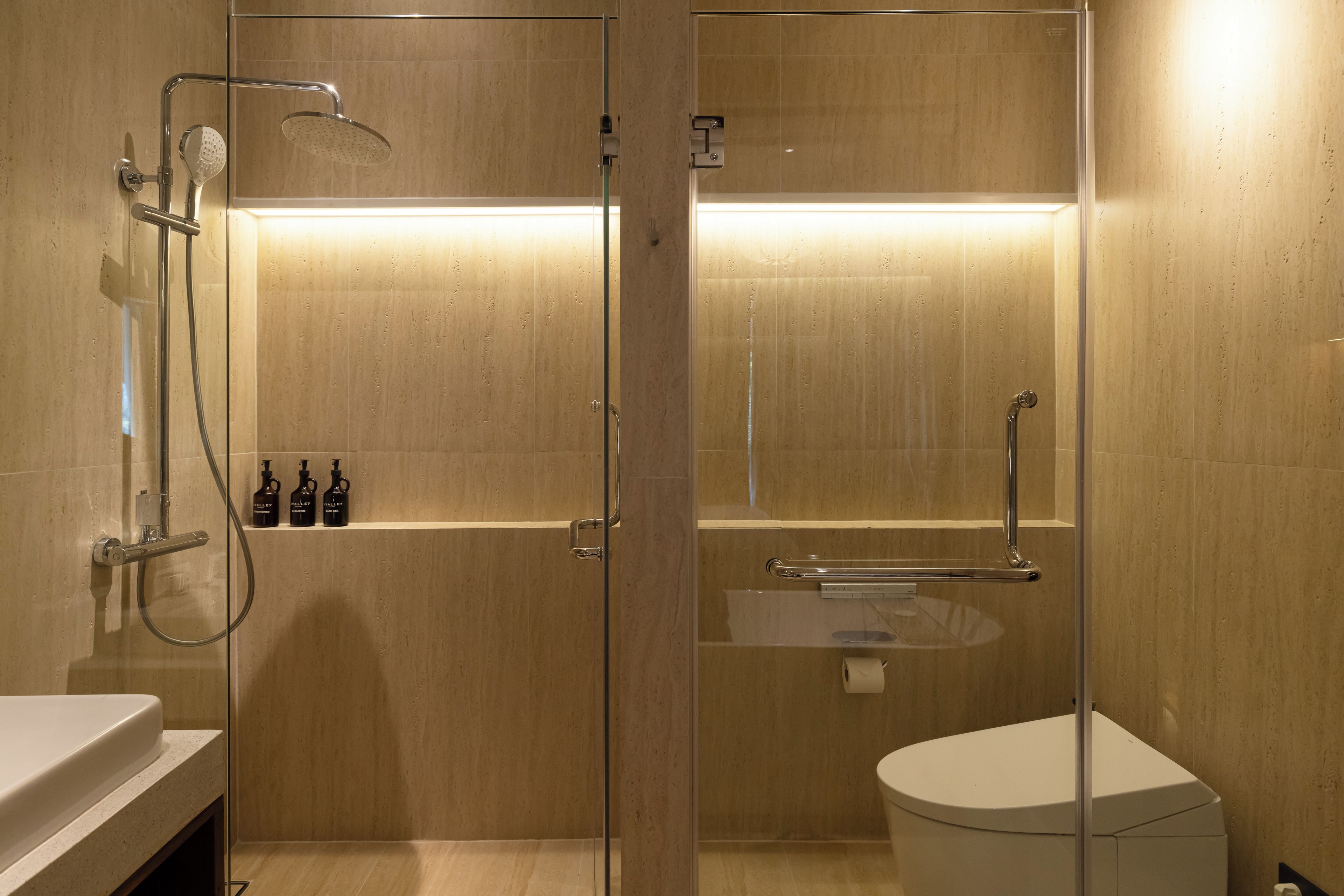 Un baño moderno con ducha envuelta en vidrio, inodoro y lavamanos.