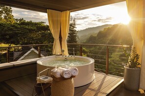 Ein Whirlpool auf einer Holzterrasse mit Blick auf ein Tal und Berge.