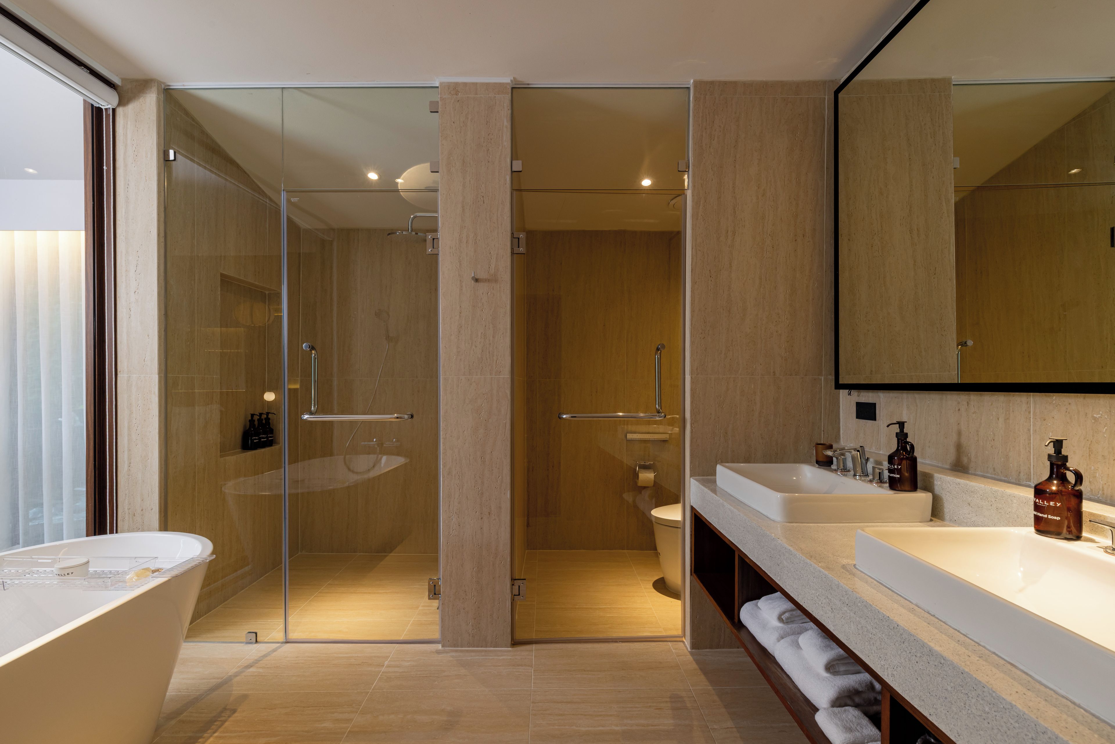 Un baño moderno con ducha envuelta en vidrio, una bañera independiente y un tocador con un espejo grande.