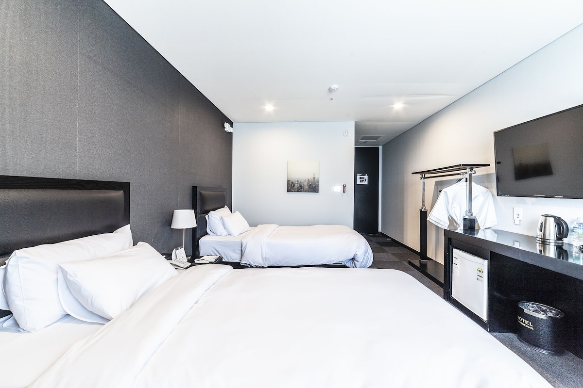 Een hotelkamer met twee bedden, een bureau met spiegel, een koffiezetapparaat en een klein kastje.
