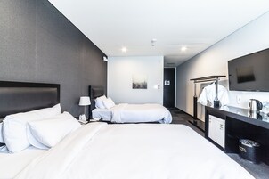 A hotel room with two beds, a desk with a mirror, a coffee maker, and a small cabinet.