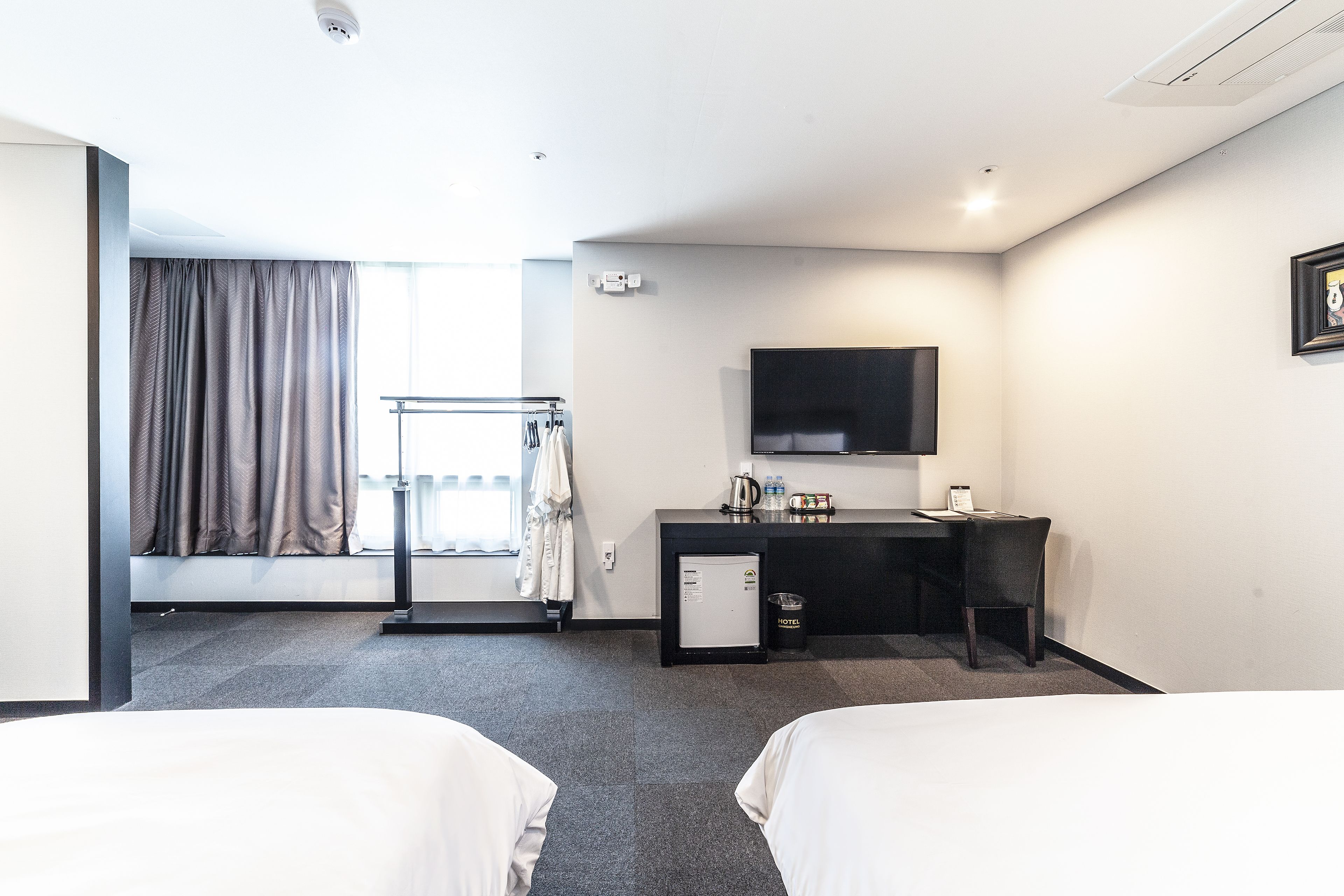 Une chambre d’hôtel avec deux lits, un bureau, une télévision et un petit réfrigérateur.