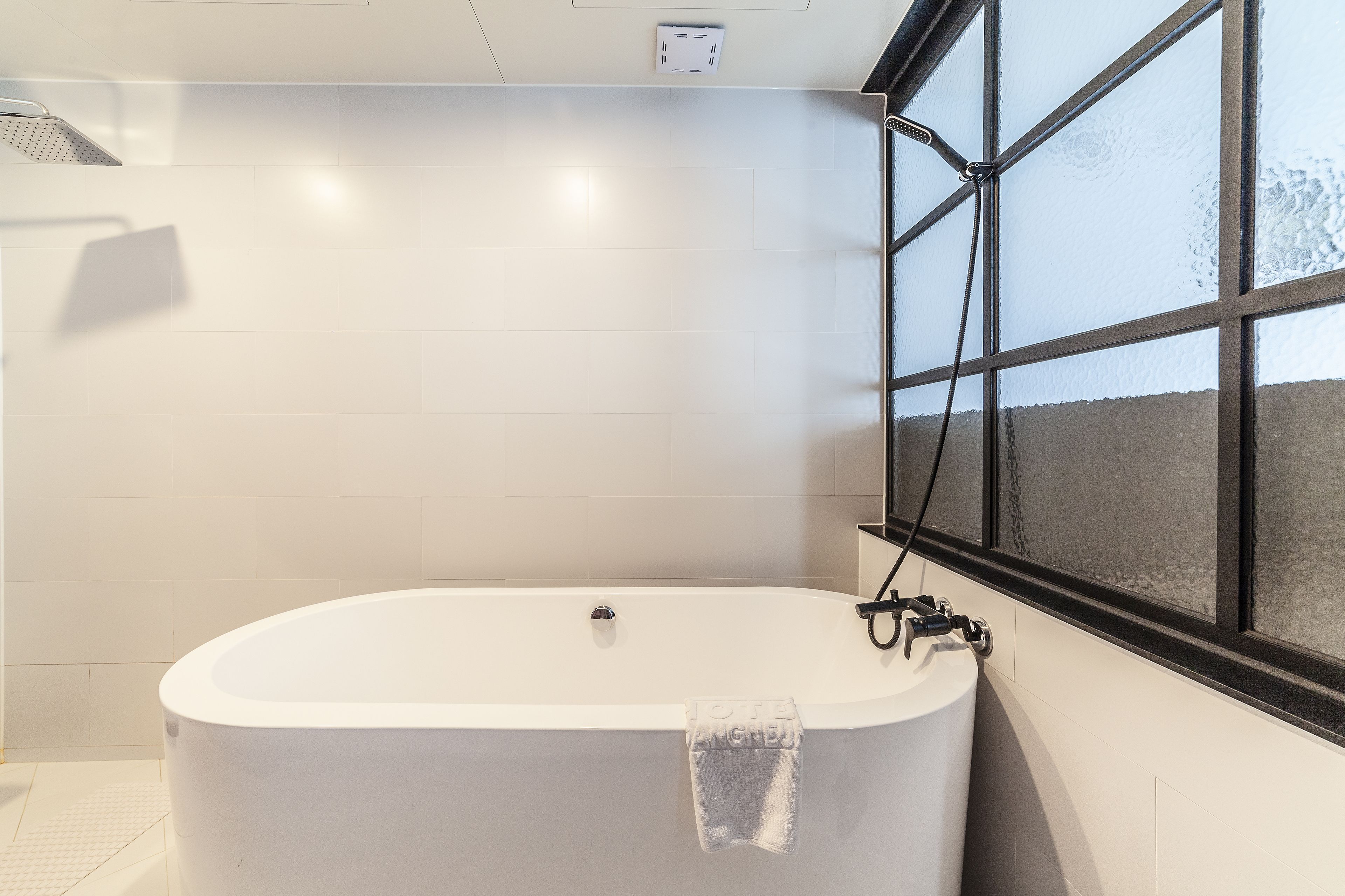 A modern bathroom with a freestanding bathtub, a window with a view, and a towel hanging on the tub.