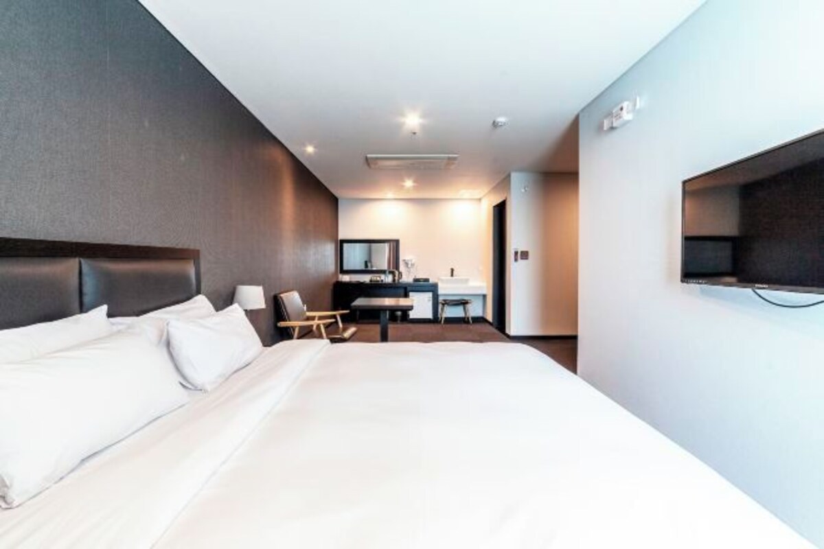 Een moderne hotelkamer met een groot bed, een bureau en een aan de muur bevestigde televisie.