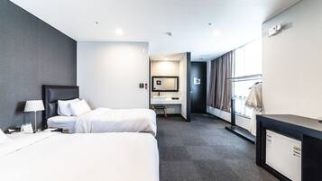 Une chambre d’hôtel avec deux lits, un bureau, un miroir et une armoire.