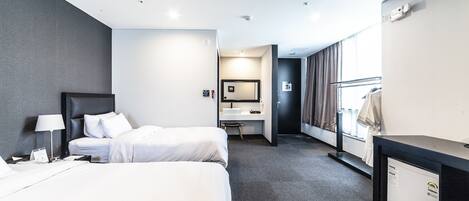 A hotel room with two beds, a desk, a mirror, and a wardrobe.