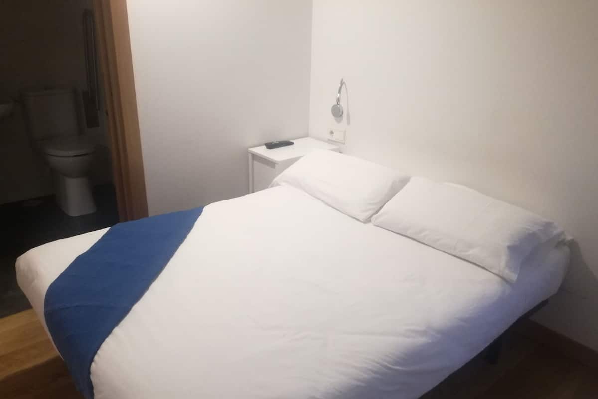 A bedroom with a bed, a bedside table, and a nightstand.