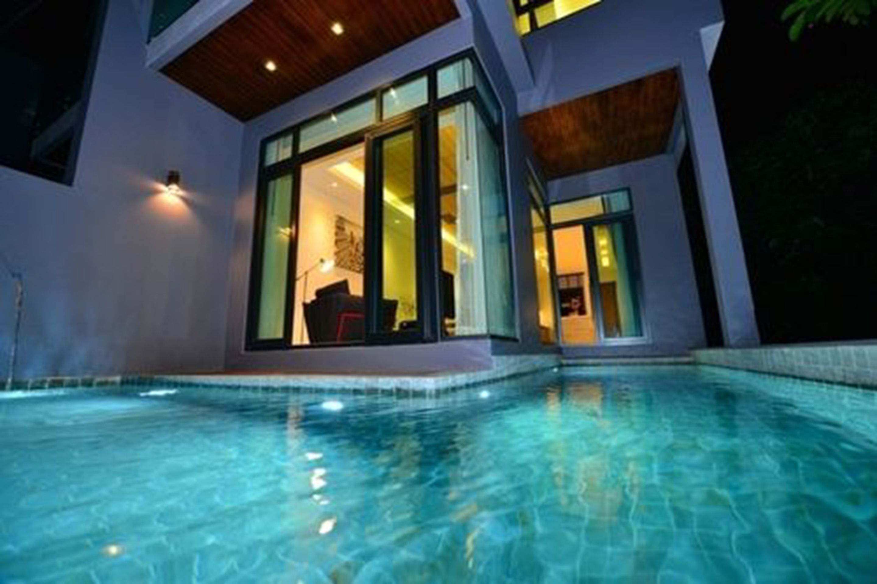 A modern house with a swimming pool, large glass doors, and a wooden ceiling.
