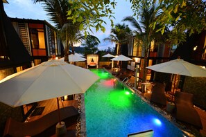 A pool area with umbrellas, lounge chairs, and a view of the surrounding buildings. - Bukit Pool Villas (Patong)