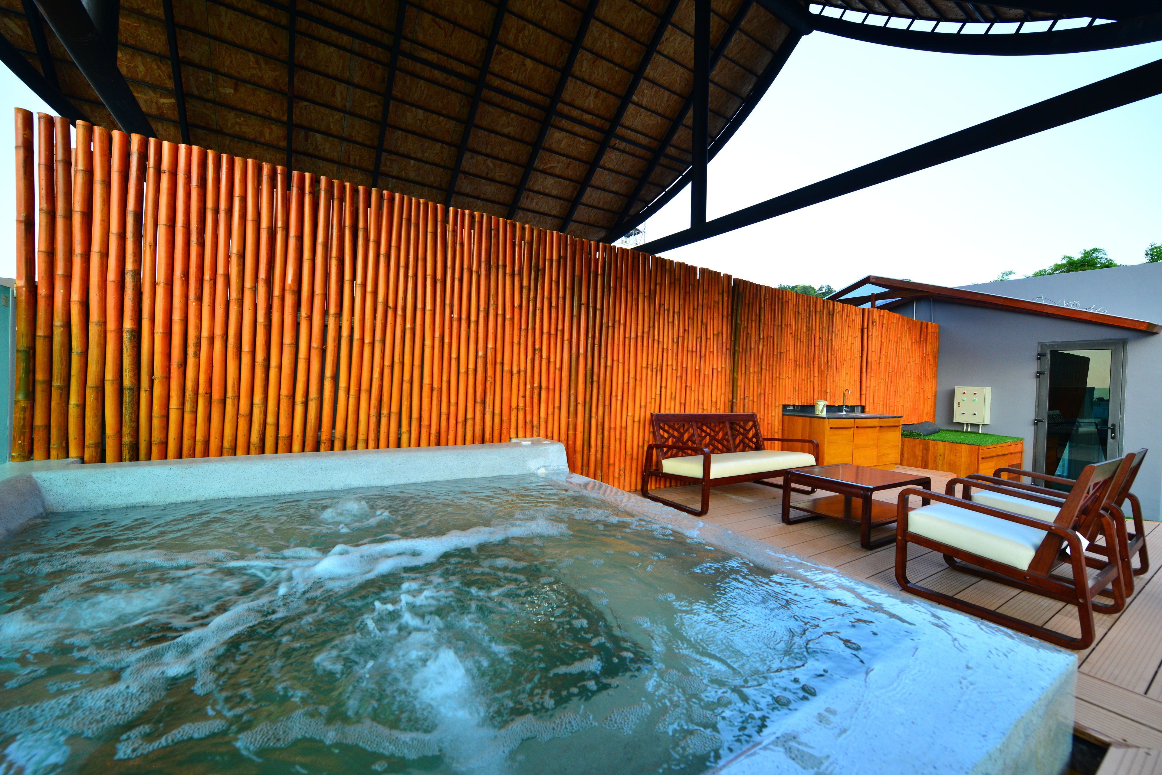 A hot tub area with wooden slats, a wooden bench, and a small kitchen area.