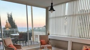 Un balcon spacieux offrant une vue sur la mer, aménagé avec un canapé, des fauteuils et une petite table.