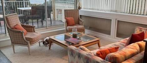 A spacious balcony with a view of the sea, furnished with a sofa, chairs, and a small table.